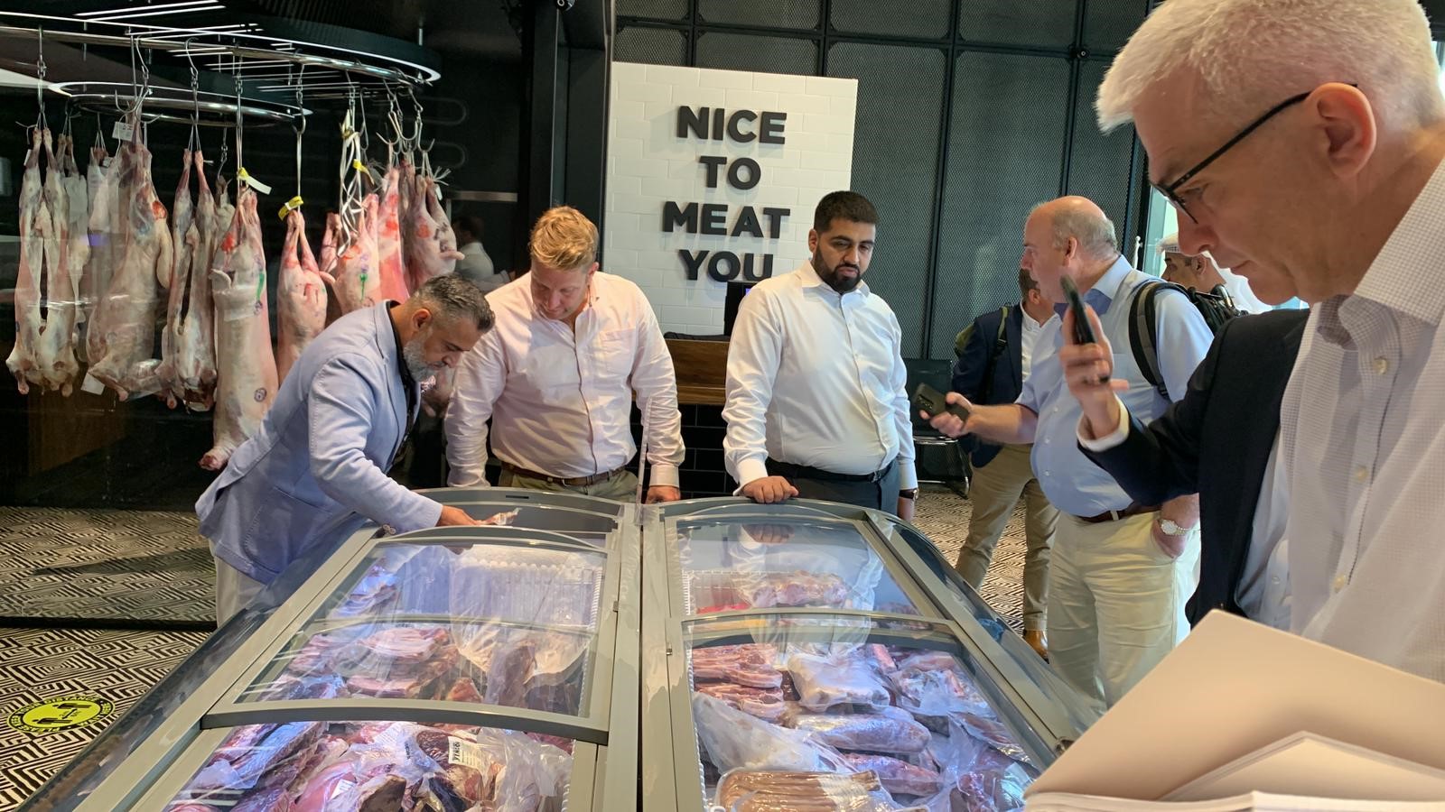 A crowd of attendees around meat fridge at Kuwait Trade mission.